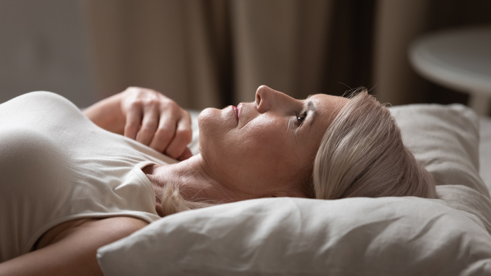 Disturbed mature older woman lying awake in uncomfortable bed look up suffer from chronic insomnia concept, anxious middle aged senior lady insomniac can not sleep on bad pillow mattress, side view